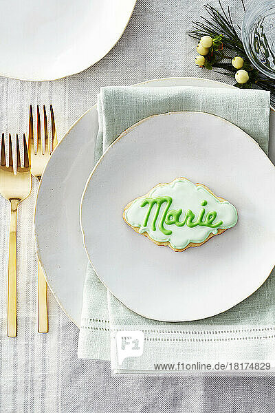 Sugar cookie place card with name in icing on a dinner plate in a festive place setting