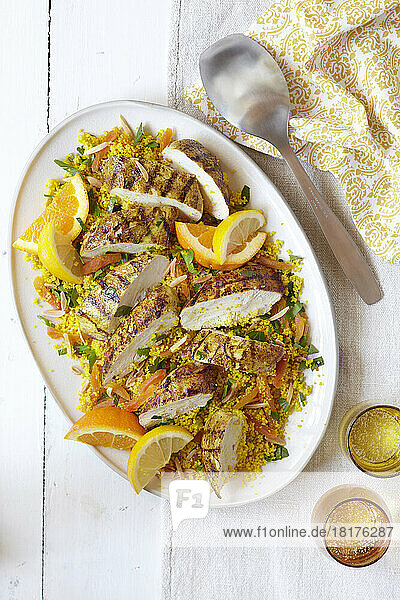 Platter of sliced chicken breast on couscous with orange and lemon slices
