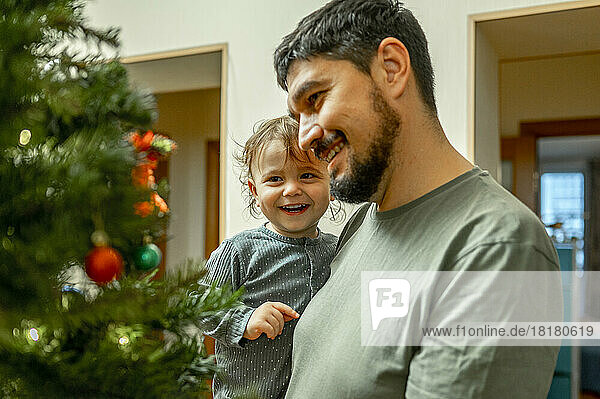 Lächelnder Vater und Sohn schauen auf den Weihnachtsbaum