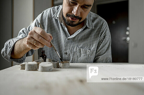 Craftsman brushing oil on wood using paintbrush at home