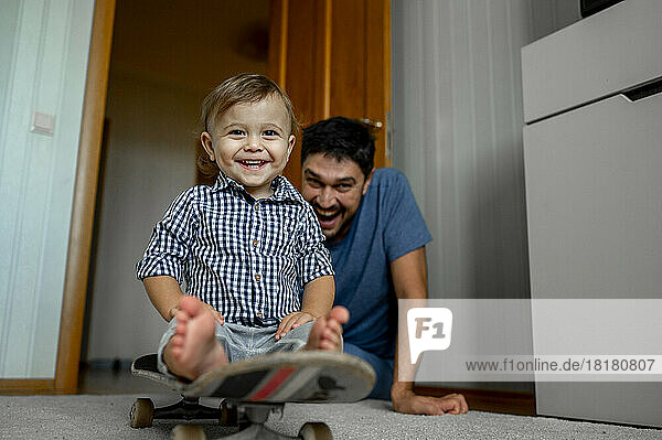 Happy father with baby boy sitting on skateboard