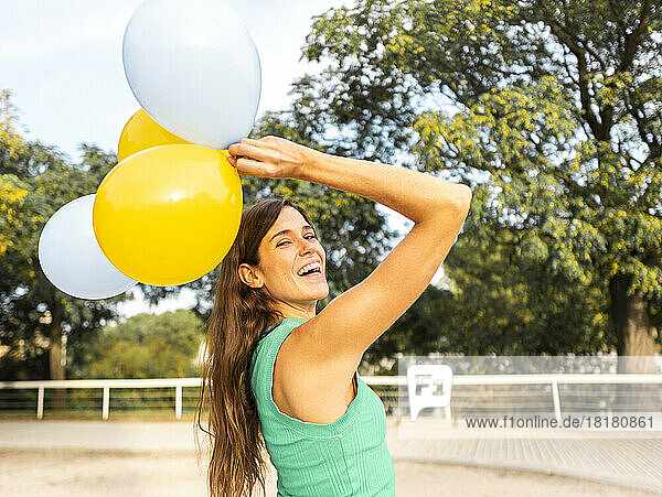 Fröhliche Frau  die Spaß mit Luftballons am Fußweg hat