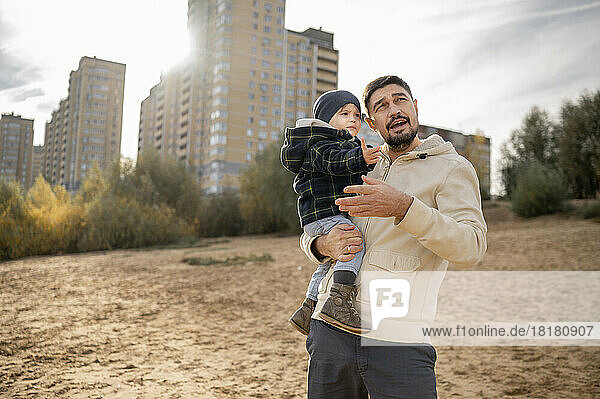 Father with son standing in front of building on sunny day at beach