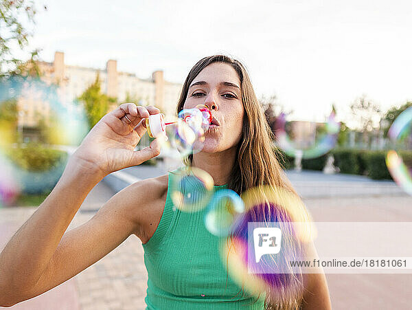 Woman blowing colorful bubbles at footpath
