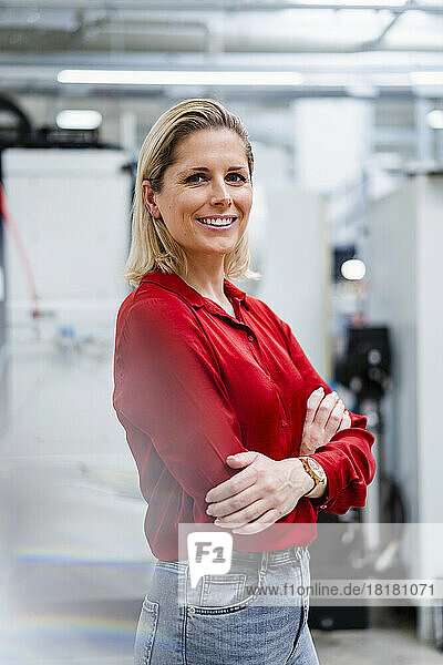 Smiling businesswoman with arms crossed standing in industry