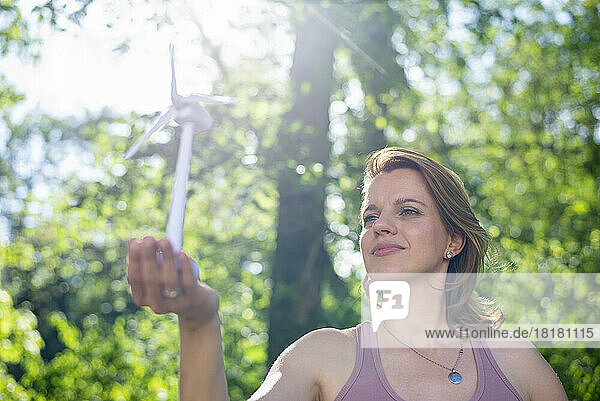 Frau hält an sonnigem Tag Windturbinenmodell im Park