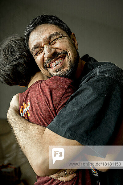 Cheerful father hugging son at home