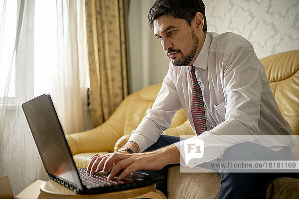 Freelancer using laptop sitting on sofa at home
