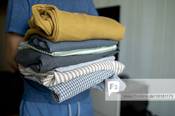 Man holding ironed folded clothes at home