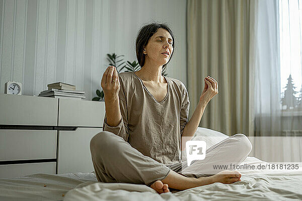 Meditierende Frau sitzt zu Hause im Bett