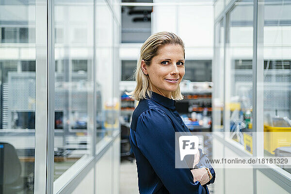 Blond businesswoman with arms crossed at factory
