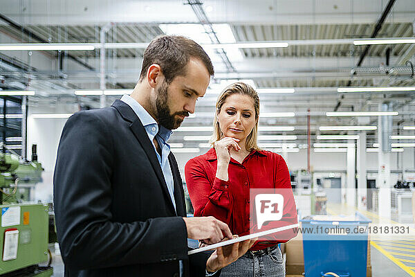 Businessman using tablet PC with colleague at factory