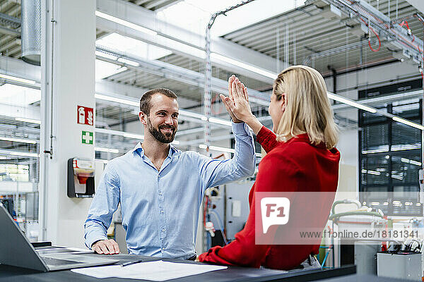 Businessman giving high-five to colleague at factory