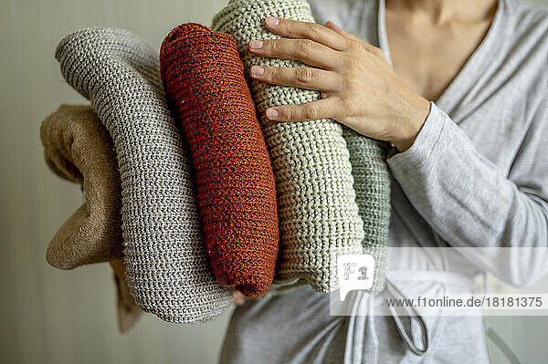 Woman holding clean folded sweaters at home