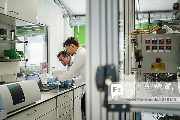 Scientists discussing over laptop in laboratory
