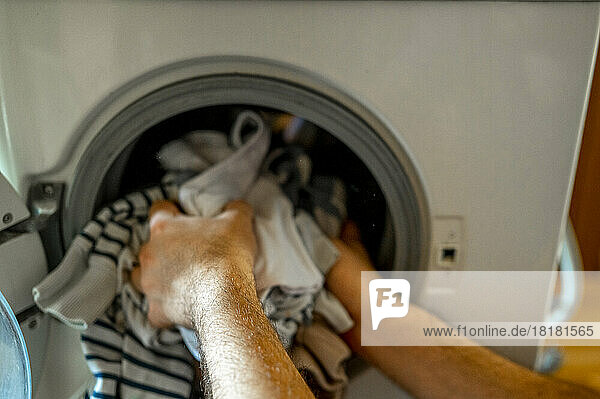 Hands of man removing clothes from washing machine