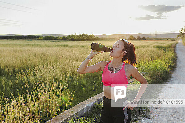 Woman drinking water from bottle on sunny day