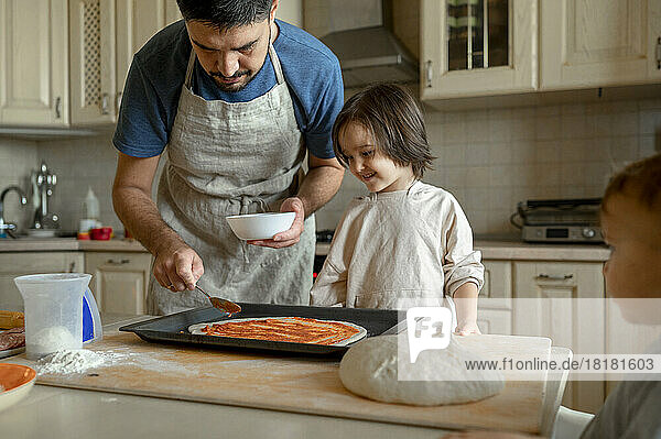 Happy boy with father preparing pizza at home