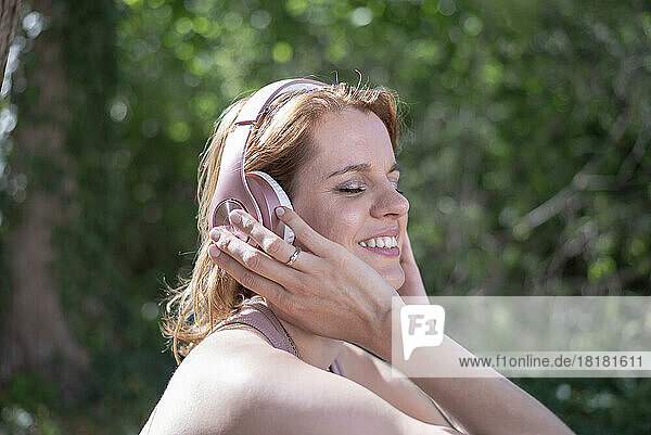 Glückliche Frau mit Kopfhörern  die im Park Musik hört