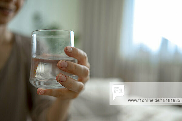 Woman holding glass of water at home
