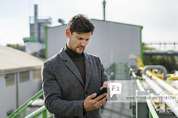 Businessman using smart phone at industrial plant