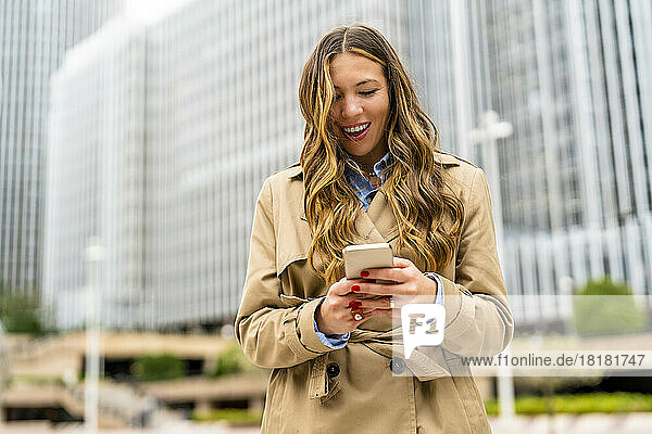 Surprised businesswoman using smart phone in front of office building