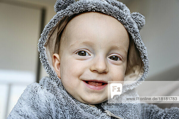 Smiling cute boy wearing gray hood at home