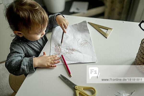 Boy scribbling with pencil on paper at home