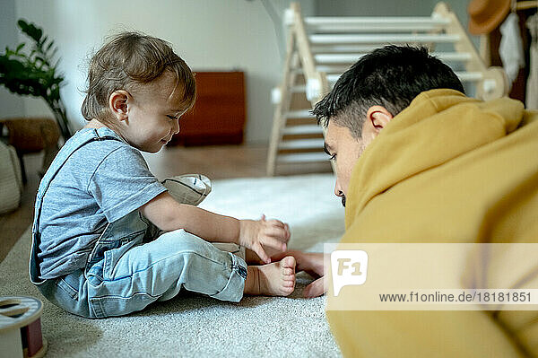 Father playing with son on carpet at home