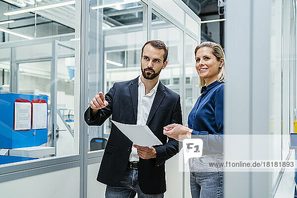 Businessman holding document pointing by colleague at factory