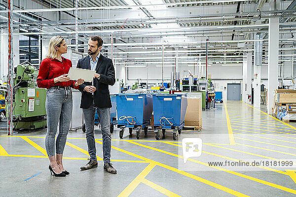 Business colleagues discussing with each other standing by markings in production hall