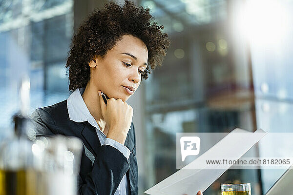 Geschäftsfrau mit Hand am Kinn liest Dokument im Büro