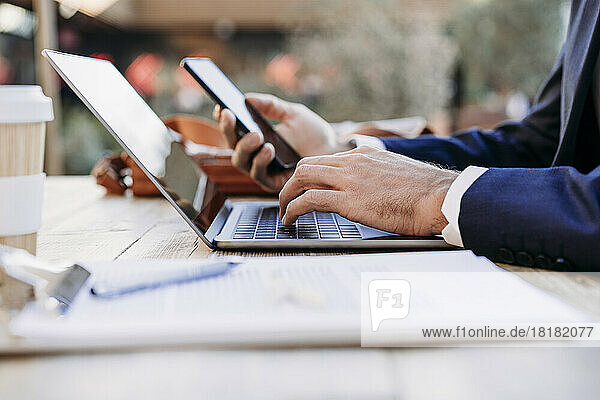 Hands of businessman working with wireless technologies at table