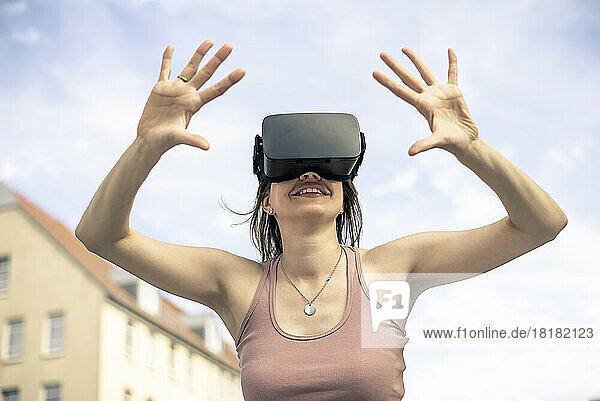 Frau mit Virtual-Reality-Simulatorbrille steht vor dem Himmel