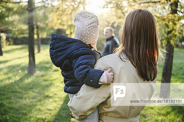 Mother carrying daughter in autumn park
