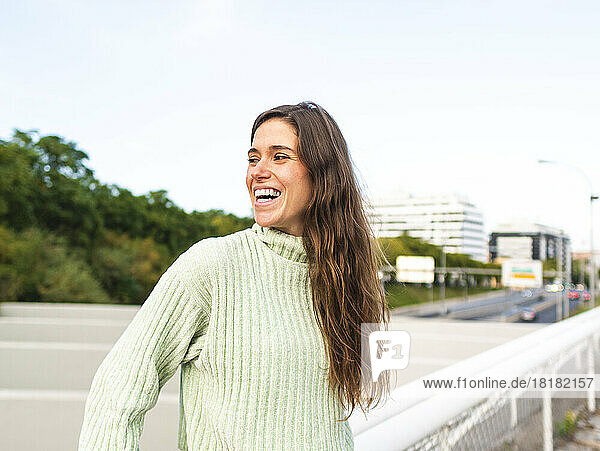 Cheerful woman wearing turtleneck sweater standing by railing