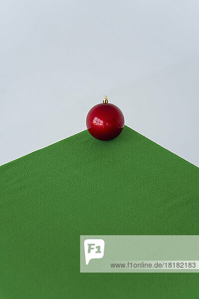 Red Christmas ornament on green velvet cloth over white background