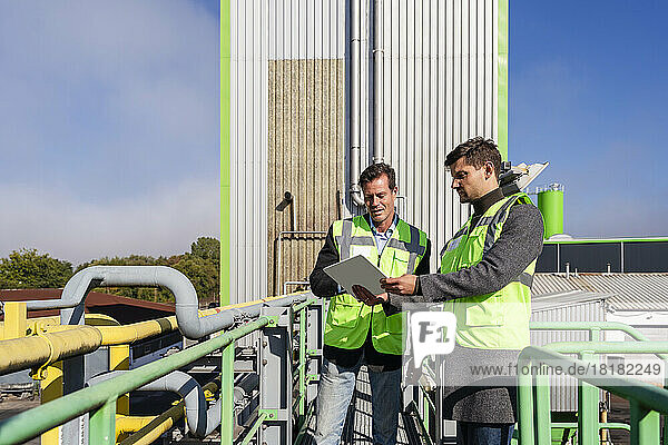 Engineers discussing over tablet PC at recycling plant