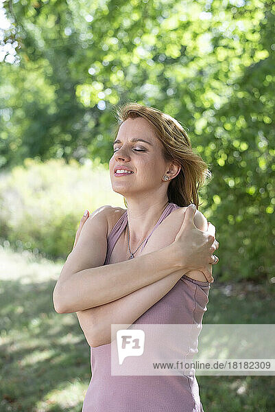Lächelnde Frau umarmt sich im Park
