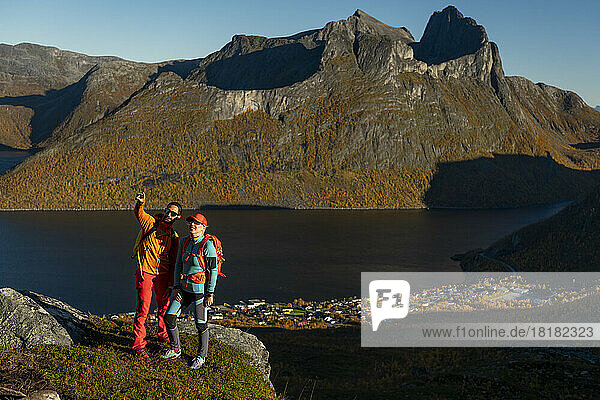 Couple standing on top of mountain and gesturing at sunny day