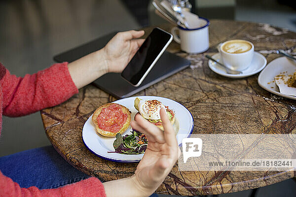 Freelancer using smart phone at table in cafe