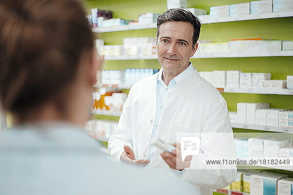 Pharmacist giving medicine to customer at pharmacy