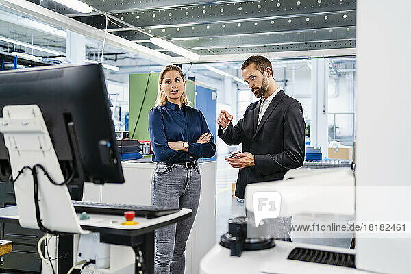 Businessman discussing with colleague over computer in factory