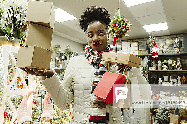Woman with Christmas gifts standing in store
