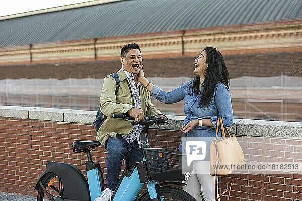 Happy mature couple with electric bicycle by wall