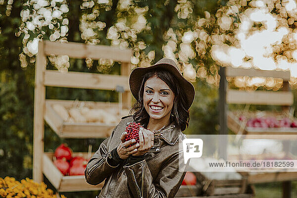 Smiling woman holding berry fruits at market