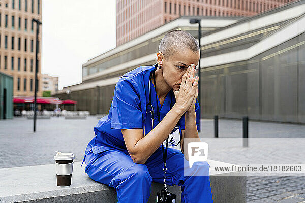 Worried female nurse contemplating on bench