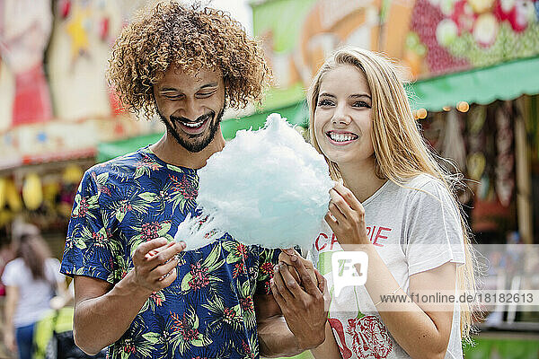 Young couple eating candy floss at a fun fair