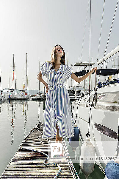 Happy young woman standing by boat on jetty