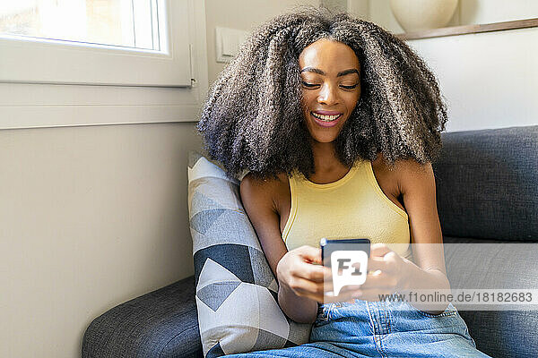 Woman with Afro hairstyle using mobile phone at home